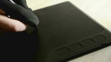 a designer's hand in a black glove draws several lines on the workspace of a graphics tablet,close up video