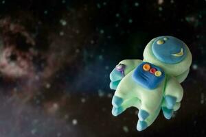 Astronaut in space. Cute cosmonaut made of plasticine against the background of nebulae and space photo