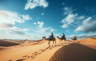 People riding camels on a sand dune in the desert photo