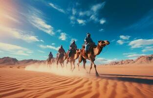 People riding camels on a sand dune in the desert photo