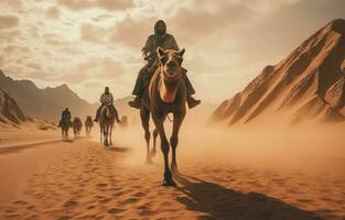 People riding camels on a sand dune in the desert photo