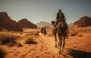 People riding camels on a sand dune in the desert photo