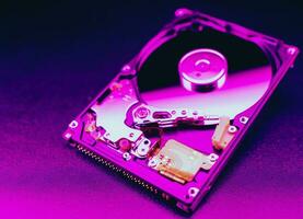 An open hard disk disassembled HDD of a computer or laptop lies on a purple surface. Computer hardware and accessories. Hard disk storage. photo