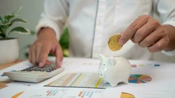 Man putting coins into piggy bank and using personal income tax calculator to pay taxes. Financial research. Report. Calculation tax return. Make a financial plan. tax deduction photo