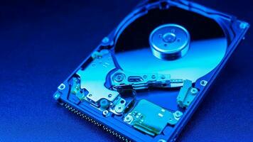 An open hard disk disassembled HDD of a computer or laptop lies on a blue surface. Computer hardware and accessories. Hard disk storage. photo