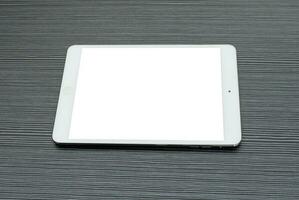 Concept for advertisement and brochure. A tablet with white screen isolated on a textured table. photo