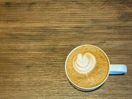 latté coronado con en forma de hoja Leche espuma y madera grano mesa foto