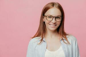 Happy entrepreneur, straight hair, spectacles, positive smile. Good sales, profits. Stylish shirt. Pink background. Copy space for text. photo