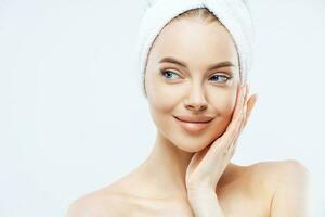 Model with makeup, touches cheek, fresh skin after bath, towel on head, isolated photo