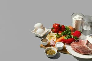 Fresh ingredients for cooking lagman on wooden board on grey background with a copy space photo