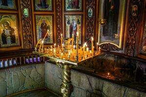 Burning candles on a stand near the icons in the chapel. photo