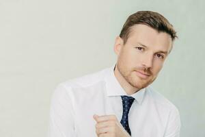 Handsome entrepreneur in white shirt looks at camera, listens attentively to interlocutor, talks business. Isolated on white background. photo