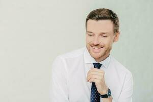 Professional office manager giggles positively, dressed in white shirt and tie. Isolated on white background. Copy space available. photo