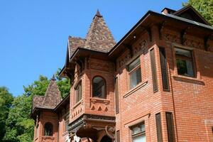 Part of the brick building of red brick and shingles on the roof photo