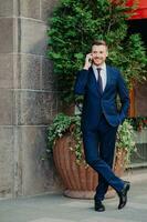 Attractive director calls manager, holds cell phone, speaks with client. Formal suit, crossed legs. Happy expression. People, business, technology. photo