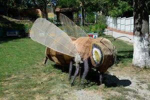 A statue of a bee made of soft material on the lawn near the apiary. photo