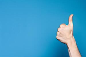 Realistic thumb up hand gesture on blue background with copy space. Like. Good feedback, positive reaction. Validation and approval. Empty space for text. . photo