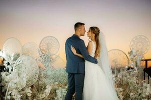 novia y novio contra el telón de fondo de una puesta de sol amarilla foto