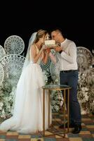 newlyweds happily cut and taste the wedding cake photo