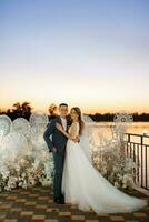 novia y novio contra el telón de fondo de una puesta de sol amarilla foto