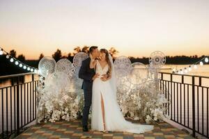 novia y novio contra el telón de fondo de una puesta de sol amarilla foto