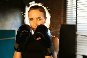 mujer yo defensa niña fuerza. fuerte mujer combatiente puñetazos con boxeo guantes a cámara. sano fuerte niña puñetazos formación puñetazos mirando concentrado derecho. ajuste cuerpo ejercicio. foto