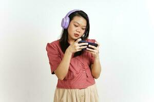 jugando móvil juego en teléfono inteligente con auricular de hermosa asiático mujer aislado en blanco foto