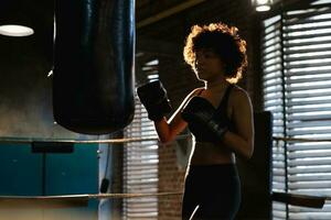 mujer yo defensa niña fuerza. africano americano mujer combatiente formación puñetazos en boxeo anillo. sano fuerte niña puñetazos boxeo bolsa. formación día en boxeo gimnasia. fuerza ajuste cuerpo rutina de ejercicio capacitación. foto