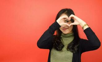 Showing Love Sign Of Beautiful Asian Woman Isolated On Red Background photo