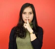 Shh Be Quiet and Looking at camera with serious face Of Beautiful Asian Woman Isolated On Red Background photo