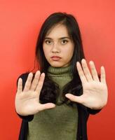 Stop Rejection Gesture Of Beautiful Asian Woman Isolated On Red Background photo