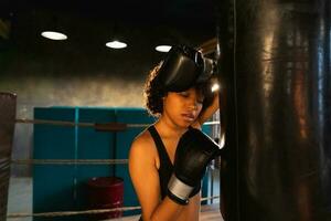 mujer yo defensa niña fuerza. africano americano mujer combatiente descansando después lucha formación en boxeo anillo. niña cansado después puñetazos boxeo bolsa. formación día en gimnasia, fuerza ajuste cuerpo rutina de ejercicio formación foto