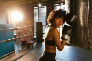 mujer yo defensa niña fuerza. africano americano mujer combatiente descansando después lucha formación en boxeo anillo. niña cansado después puñetazos boxeo bolsa. formación día en gimnasia, fuerza ajuste cuerpo rutina de ejercicio formación foto