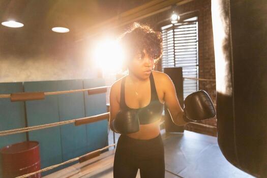 mujer yo defensa niña fuerza. africano americano mujer combatiente formación puñetazos en boxeo anillo. sano fuerte niña puñetazos boxeo bolsa. formación día en boxeo gimnasia. fuerza ajuste cuerpo rutina de ejercicio capacitación. foto