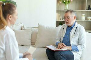 Senior man doctor examining yound woman in doctor office or at home. Girl patient and doctor have consultation in hospital room. Medicine healthcare medical checkup. Visit to doctor. photo