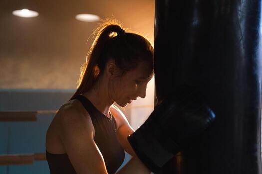 mujer yo defensa niña fuerza. fuerte mujer combatiente descansando después lucha formación en boxeo anillo. fuerte niña cansado después puñetazos boxeo bolsa. formación día en gimnasia. fuerza ajuste cuerpo rutina de ejercicio capacitación. foto