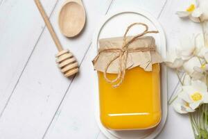 Jar with honey and flowers on wooden background top view, flat lay photo