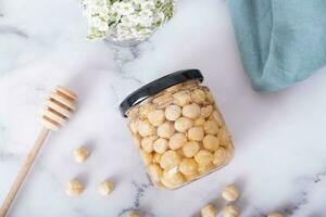 Glass jar with honey nuts and nuts on wooden background. Hazelnuts in honey. Top view photo