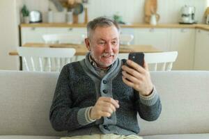 Happy middle aged senior man talk on video call with friends family. Laughing mature old senior grandfather having fun speaking with grown up children online. Older generation modern tech usage. photo