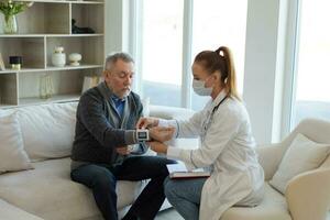 Female doctor senior man taking his blood pressure in doctor office or at home. Old man patient and doctor have consultation in hospital room. Medicine healthcare medical checkup. Visit to doctor. photo