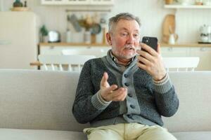 Happy middle aged senior man talk on video call with friends family. Laughing mature old senior grandfather having fun speaking with grown up children online. Older generation modern tech usage. photo