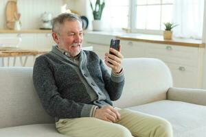 Happy middle aged senior man talk on video call with friends family. Laughing mature old senior grandfather having fun speaking with grown up children online. Older generation modern tech usage. photo