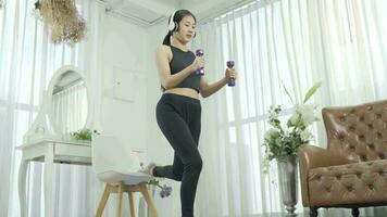 Woman losing weight at home and exercising with dumbbells. Wearing headphones listening during exercise. video