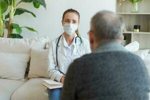 Female doctor examining older senior man in doctor office or at home. Old man patient and doctor have consultation in hospital room. Medicine healthcare medical checkup. Visit to doctor. photo