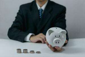 Businessperson putting coin piggy bank.Concept saving money investment, and financial planning. photo