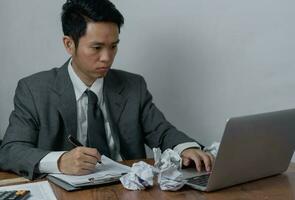 man asian working laptop computer on desk focused on his work, with a serious expression on his face. photo