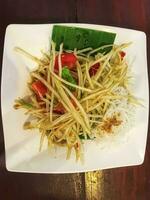 Papaya salad in a white plate, it is the staple food of Thai people. photo