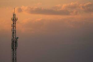 silhouette of tower under cloudy sky during sunset photo