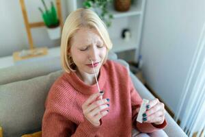 Young woman holding self testing self-administrated swab and medical tube for Coronavirus covid-19, before being self tested at home photo