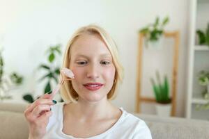 Woman doing self massage with rose quartz face roller photo